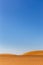 Simple minimalist desert landscape with golden sand dunes, low horizon, crystal blue sky, copy space, background