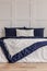 Simple navy blue and white bedroom interior with cozy bed with pillows and duvet