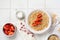 Simple oatmeal porridge with strawberries in a white plate on a linen napkin. Breakfast health food concept. Top view