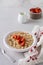 Simple oatmeal porridge with strawberries in a white plate on a linen napkin. Breakfast health food concept. Top view