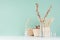 Simple organic beige wooden home decor with dried plants in glass bottles, twigs bunch, wicker basket in green mint menthe color.