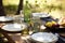 a simple picnic table setting with plates, silverware and glasses