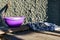 A simple purple plastic plate, outdoor tableware for feeding animals, cats and dogs, stands on dusty wooden planks