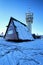 Simple roofed mountain chalet with modern broadcasting tower