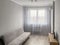 A simple room interior with a gray silver sofa with a sideboard and a TV opposite, with gray textured walls and white tulle on the