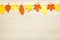 Simple, rustic country style Fall Thanksgiving decorations garland banner of colorful cut paper leaves on whitewashed wood