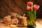Simple rustic still life of red tulips in a green glass and stacks various cookies on wooden table.