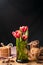 Simple rustic still life of red tulips in a green glass and stacks various cookies on wooden table.