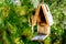 Simple rustic wooden birdhouse hanging against greenery background