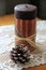 Simple scene of Americana candle and pinecone on lace table runner