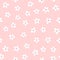 Simple seamless pattern with repeated white flowers on pink background.