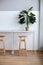 Simple Sitting area with table, high chairs and plant in pots. Minimalist design with of table and high bar stools for coffee shop