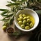 simple still life with white bowl filled with olive oil and olives and leaves from olive tree as decortation