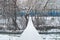 Simple suspension rope bridge hanging over a mountain river covered with snow with a train passing on winter background