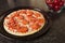 Simple uncooked pepperoni pizza on a metal round cooking tray. Italian world known dish with dough, cheese and meat and sauce