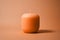 A simple unlit peach fuzz color candle on minimal background
