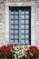 Simple vertical picture of stone covered window with flower variations in front