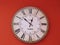 Simple wall clock with roman numerals. deep red background