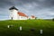 Simple white church and tower sit in plain grounds before a large grand residence in Iceland