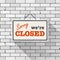 Simple white sign with text `Sorry we`re closed` hanging on a gray brick wall. Creative business interior template