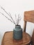 Simple willow buds branches in stylish vase on wooden rustic chair in home. Hello spring concept. Countryside living. Modern rural