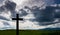 Simple wooden catholic cross silhouette, dramatic storm clouds