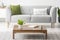 Simple, wooden coffee table in front of a gray settee with fashionable pillows in a monochromatic living room interior