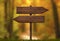 Simple wooden double direction arrow roadsign with autumn forest background