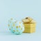 Simplicity and minimal design of easter eggs with gold dots with gift box on blue background, square.