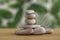 Simplicity stones cairns on green and white background, group of light gray pebbles built in tower, wood table