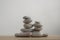 Simplicity stones cairns isolated on white background, group of light gray pebbles built in towers, wood table