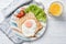 Simply breakfast with fried egg on a toast bread and vegetables with orange juice, top view