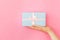 Simply design female woman hand holding blue gift box isolated on pink pastel colorful trendy background