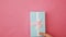 Simply design female woman hand holding blue gift box isolated on pink pastel colorful trendy background