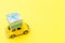 Simply design yellow vintage retro toy car delivering gift box on roof isolated on trendy yellow background. Christmas New Year