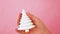 Simply minimal design female woman hand holding Christmas ornament fir tree isolated on pink pastel colorful trendy