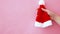 Simply minimal design female woman hand holding Christmas ornament Santa hat isolated on pink pastel colorful trendy