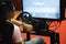 Simulation of race car video player game with big screen monitors and cockpit controls like a racing car.