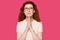 Sincere redhead woman holds hands together praying pose over pink