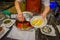 SINGAPORE, SINGAPORE - JANUARY 30. 2018: Close up of woman using a huge metallic spoon serving the penang asam laksa