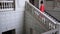 Singer in elegant red dress on high heels climbs a large staircase at beautiful hall