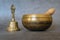 Singing bowl and golden bell close-up, soothing and meditative. Singing bowl with sanskrit engraving pattern and wooden mallet and