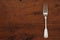 Single antique silver fork on an empty wooden table with a copy space