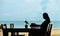 Single Asian young woman sitting at dining table on beach