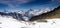 Single backcountry skier in a vast mountain landscape on his way down from a high summit with a great view of the Matterhorn and s