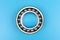 Single ball bearing close up, isolated on blue background with copy space on the sides.