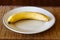 Single Banana With Some Brown Ripening Spots On Plate