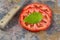 Single basil leaf and sliced tomato with knife on real stone boa