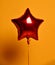 Single big red star balloon ballon object for birthday party on yellow