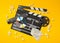 Single, black, open movie clapper or clapper-board with dvd movie disc, film reel, popcorn, remote control and movie theatre